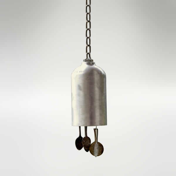 A wind bell made from a re-purposed oxygen tank and flattened spoons. It features a silvery tone and appearance. 